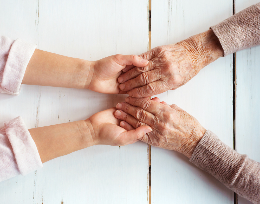 An above shot of a senior woman holding hands with a caregiver