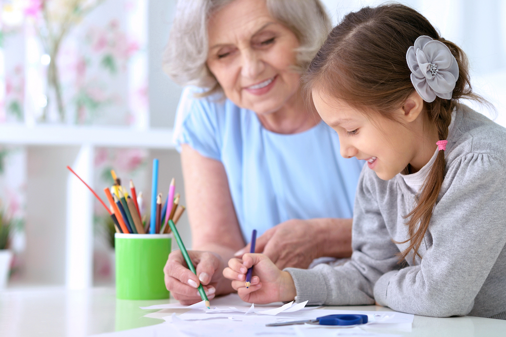 A senior woman and her granddaughter color together