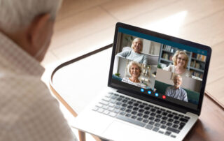 A senior man video chats with his friends on a computer